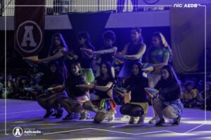 Alunos da Educacao Infantil e Ensino Fundamental se apresentando com fitas coloridas na quadra decorada durante a cerimonia de abertura das Olimpiadas Escolares 2026 no Colegio de Aplicacao de Resende.