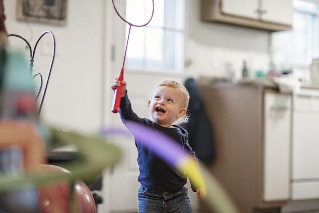 Menino brincando com uma raquete vermelha