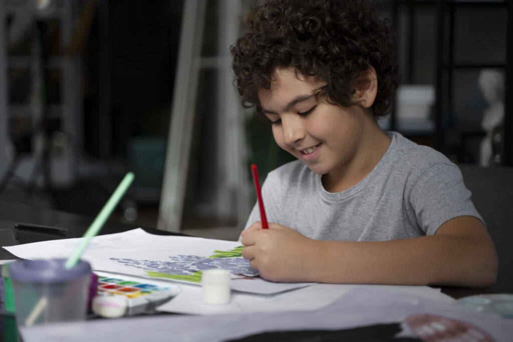 Criança com cabelo cacheado sorrindo e pintando um desenho com tinta guache, ilustrando o prazer na aprendizagem infantil e o desenvolvimento infantil artístico.