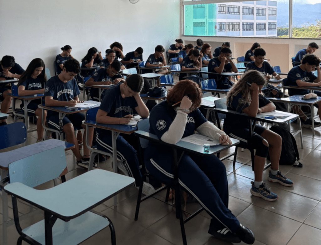 Sala de aula com estudantes do Ensino Médio do Colégio de Aplicação de Resende uniformizados e concentrados realizando a prova do Simulado ENEM em suas carteiras escolares.